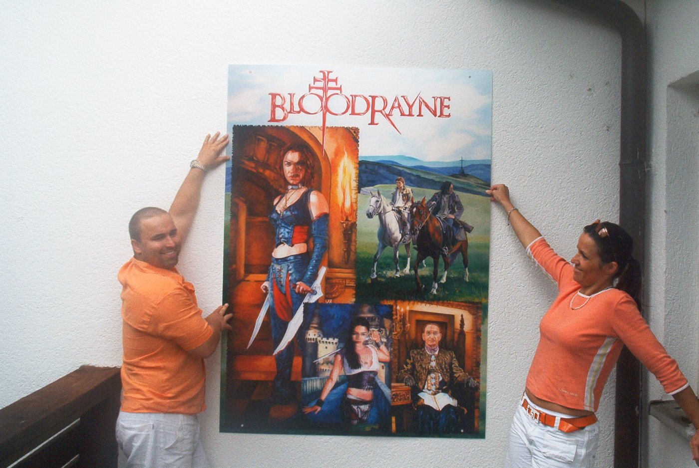 Two people putting up a large-format BloodRayne poster